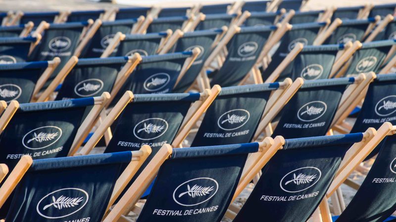 Plusieurs chaises disposées le long d’une plage à Cannes avec pour inscription au dos « Festival de Cannes »